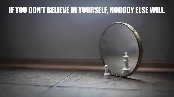 A conceptual image featuring a white chess pawn standing on a dark, textured floor. In front of the pawn is a circular mirror reflecting the pawn, which appears in the reflection as a tall, white chess king. The background is a dark, out-of-focus grey. Above the scene, white capital text reads: 'IF YOU DON'T BELIEVE IN YOURSELF, NOBODY ELSE WILL.'