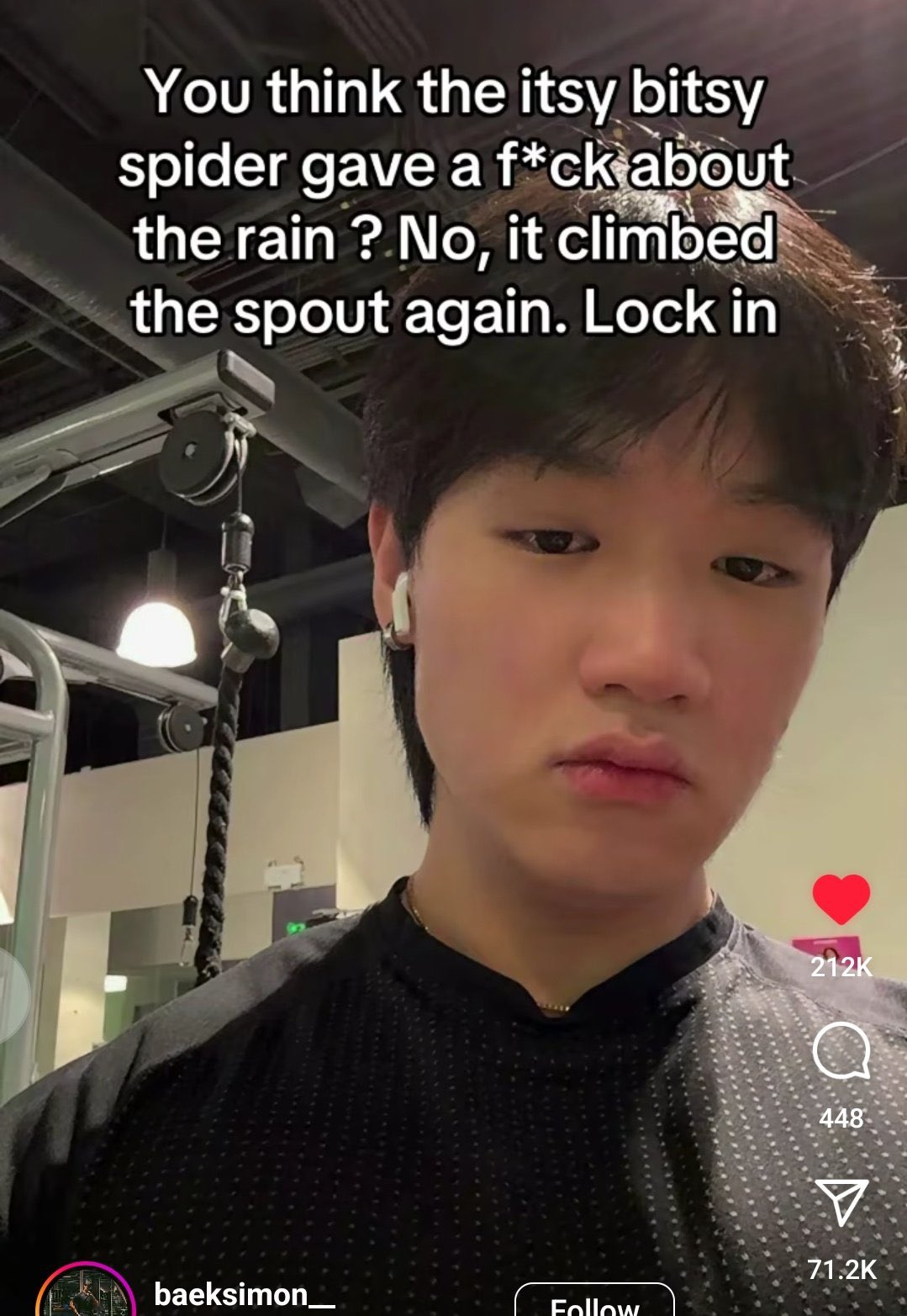 A vertical screenshot of a social media video, likely from TikTok. It features a close-up shot of a young man with dark hair and a serious expression, wearing a black textured shirt and a white wireless earbud in his right ear. He is in what appears to be a gym setting, with weightlifting equipment visible in the blurred background. Overlaid on the image is large white text that reads: 'You think the itsy bitsy spider gave a f*ck about the rain ? No, it climbed the spout again. Lock in'. On the right side, there are social media interaction icons: a red heart with '212K', a comment bubble with '448', and a share icon with '71.2K'. At the bottom, the username 'baeksimon__' is visible next to a small profile picture and a 'Follow' button.