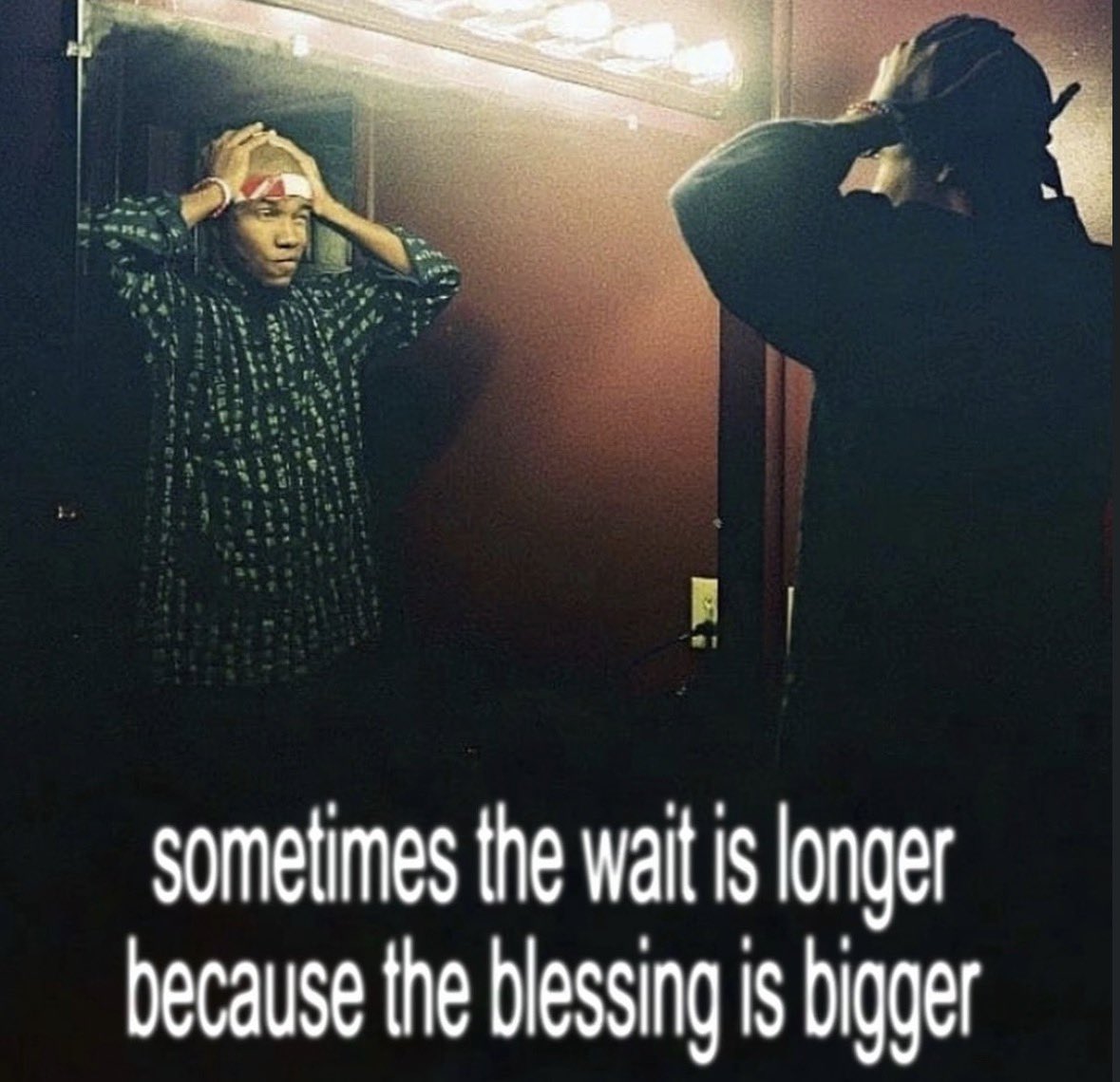 A photo of a person looking into a mirror, holding their head in their hands with a pensive or distressed expression. The person is wearing a patterned green and black shirt and a white headband. The image features inspirational text overlaid at the bottom.