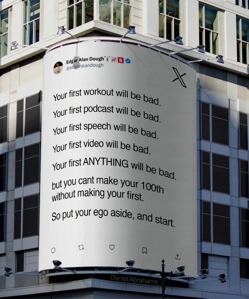 A photograph of a large, curved digital billboard mounted on the side of a modern office building. The billboard displays a simulated X (formerly Twitter) post from a user named 'Edgar Alan Dough'. The text on the billboard is motivational, stating that first attempts at anything will be bad, but one must start to reach mastery. At the bottom of the billboard, the name 'Daniel Abrahams' is visible.