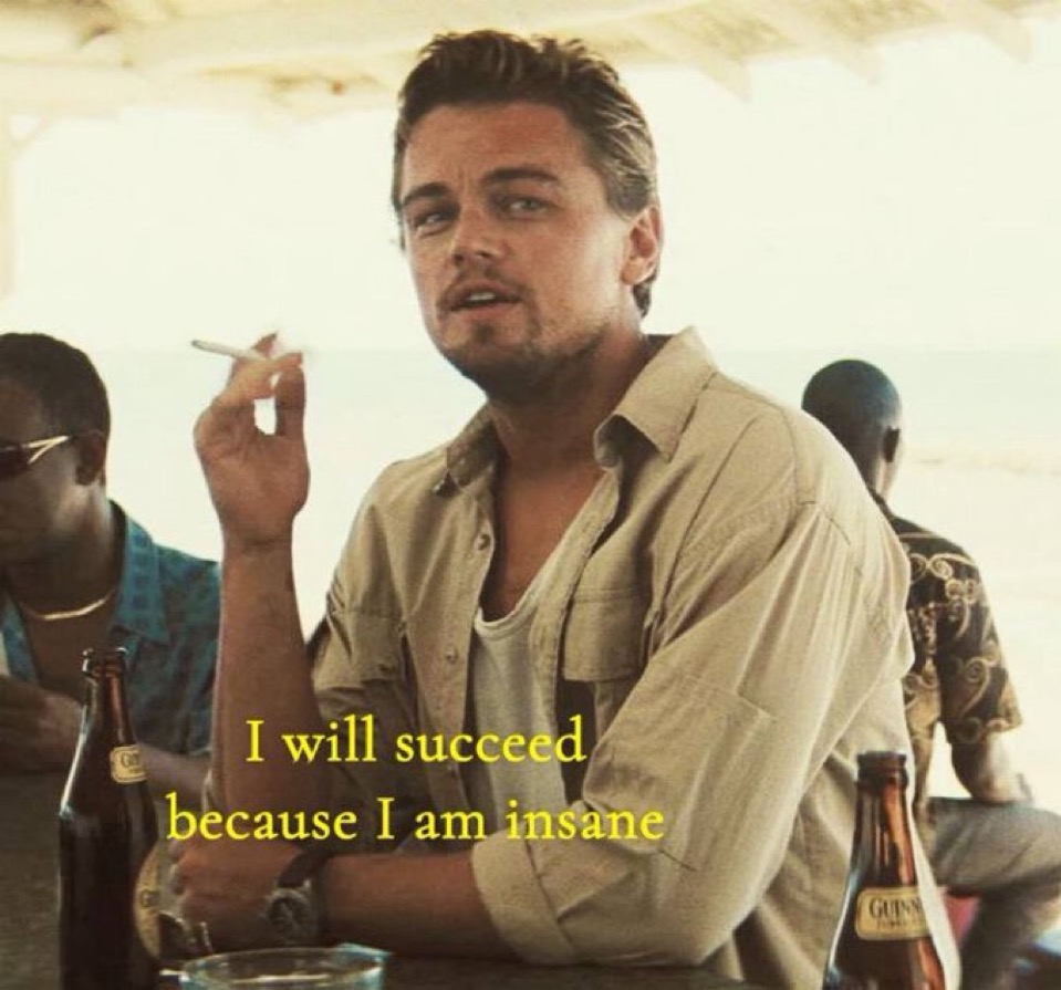 A meme featuring a medium shot of actor Leonardo DiCaprio from the movie 'Django Unchained'. He is sitting at an outdoor beachside table, wearing a tan button-down shirt over a white undershirt, holding a cigarette in his right hand. In the background, other people are visible under a shaded area near a beach. Yellow text is overlaid on the bottom half of the image.