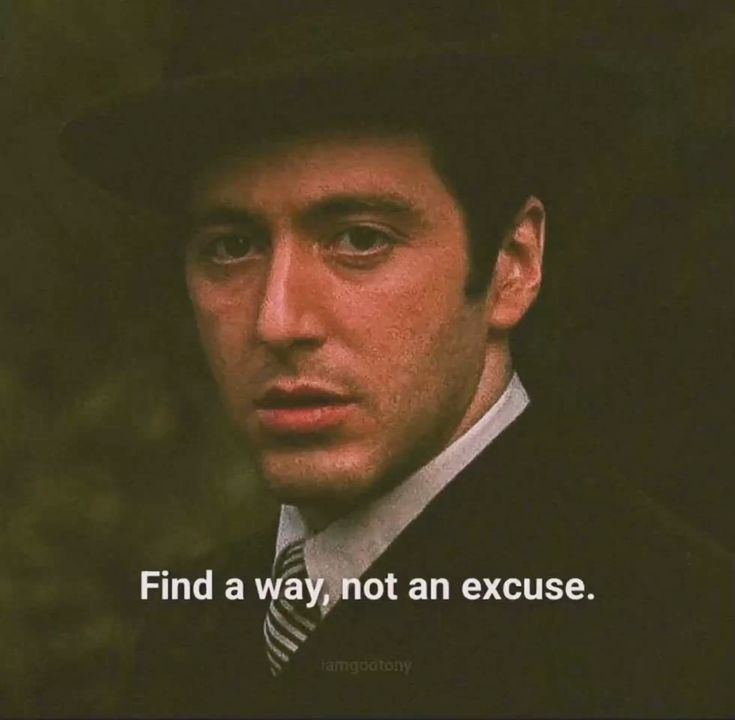 A close-up portrait of actor Al Pacino, appearing to be in character from a film (likely The Godfather), wearing a dark hat and a dark suit with a white shirt and striped tie. He has a serious, intense expression. Overlaid at the bottom of the image is motivational text, and a small watermark is visible at the very bottom center.