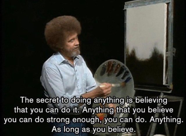 A still shot of a man with a large afro hairstyle, wearing a light blue button-down shirt. He is looking towards a large white board or canvas on a stand. Overlaid on the bottom half of the image is a block of white text on a black background.