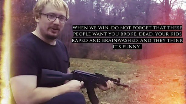 A medium shot of a man with blonde hair and glasses, wearing a black t-shirt. He is holding a black rifle. The image has a heavy light leak effect with orange and red hues overlaid on the left and right sides. In the background, there is a blurred forest setting with trees and foliage. There is white text overlaid on the center of the image.