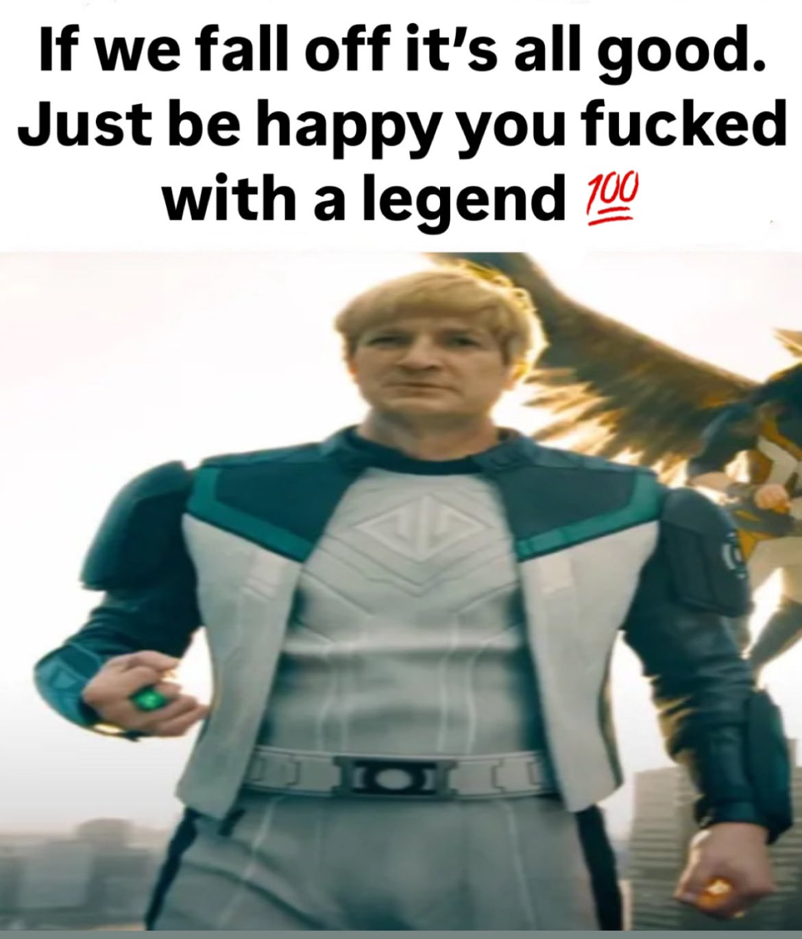 A meme featuring a character from a superhero-style production. The central figure is an older man with blond hair, wearing a white and teal superhero costume with a belt. In the background, a winged figure is partially visible. The image is topped with bold black text that conveys a defiant or boastful message.