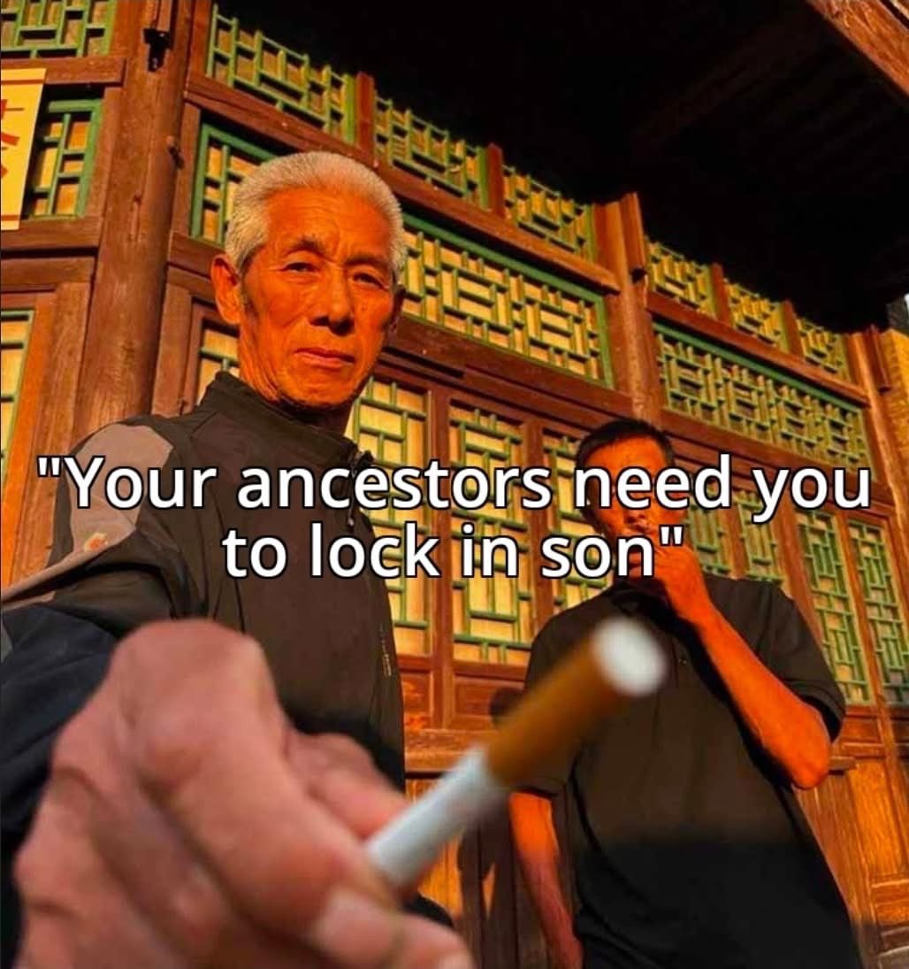 A meme featuring an older Asian man with white hair in the foreground, looking intensely at the camera while holding out a lit cigarette towards the viewer. In the background, a younger man stands in front of a traditional wooden structure with ornate green and yellow lattice patterns. The lighting is warm and dramatic, casting a strong orange glow on the subjects. Overlaid on the center of the image is white text in a sans-serif font.