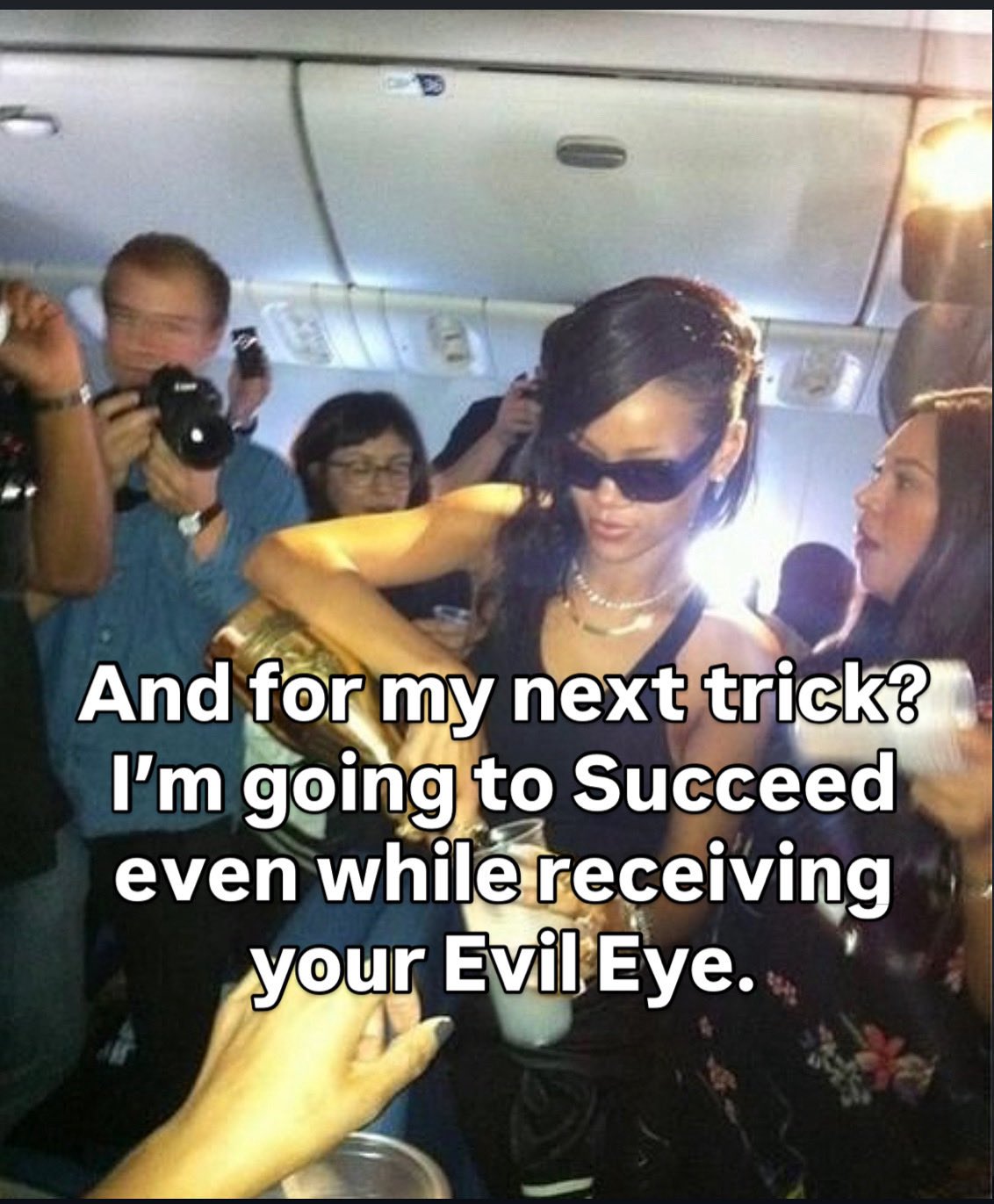 A meme featuring a photograph of singer Rihanna on an airplane, wearing sunglasses and pouring a drink from a gold bottle. She is surrounded by people, including a man taking a photo with a camera. Large white text is overlaid on the center of the image.