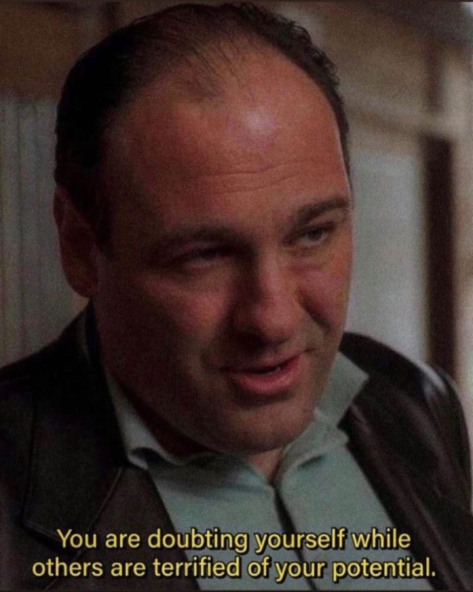 A close-up portrait of the character Tony Soprano (played by James Gandolfini) from the television series 'The Sopranos'. He has a serious, intense expression and is looking slightly to the side. He is wearing a dark jacket over a light-colored collared shirt. At the bottom of the image, there is motivational text overlaid on the frame.